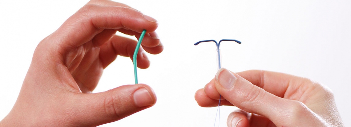Hands holding an IUD and a contraceptive implant