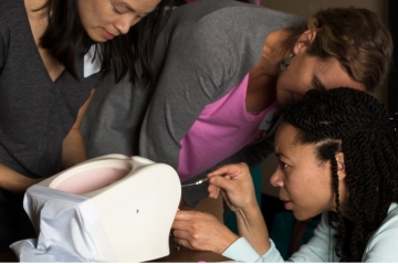 Providers practice inserting IUDs on a pelvic model.