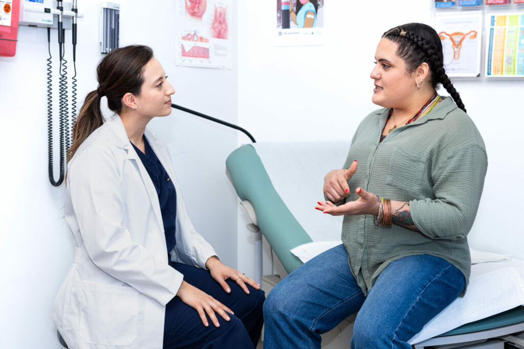 A woman sitting in a doctor's office having a conversation with her healthcare provider